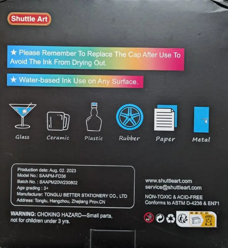 Shuttle Art 36 Colors Dual Tip Acrylic Paint Markers Review: Are They Worth It? picture of the back of the box that says "Please remember to replace the cap after use to avoid the ink from drying out. Water-based ink use on any surface". Then it  shows images of glass, ceramic, plastic, rubber, paper, and metal.